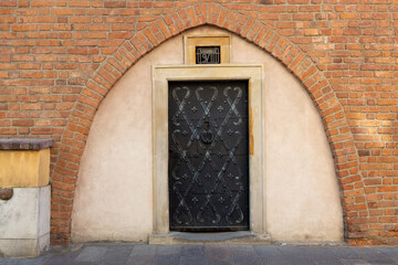 Fototapeta na wymiar Old wall with small vintage black door. Old metal entrance