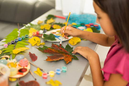 little girl artist paints autumn leaves 