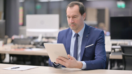 Businessman using Tablet while Sitting in Office