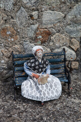 Santon représentant une vieille femme assise sur un banc et tricotant - obrazy, fototapety, plakaty