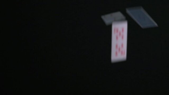 Playing cards are falling in slow motion on a black background.
