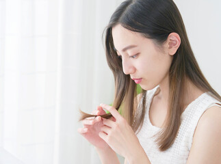 リビングで毛先を見る女性 © siro46