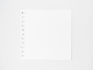 empty white square sheet of paper torn from a sketchbook on a white table. space for text, template for design