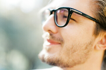 Young man with glasses squints at the sun. Profile. Portrait