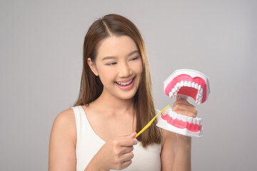 Young smiling woman holding toothbrush over white background studio, dental healthcare and Orthodontic concept..