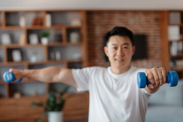 Sporty korean mature man exercising with dumbbells at home, strengthening arm muscles, selective focus on hand