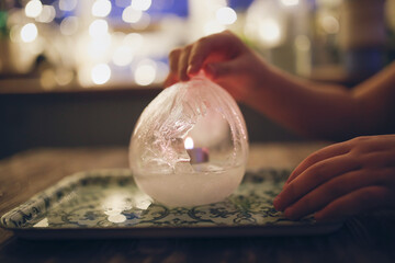 Toddler child with a candle and lamp made of ice, ice lamp.