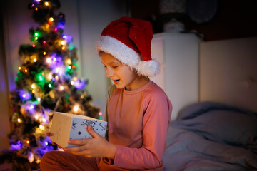 Cute preteen kid in santa hat girl with box with gift in bedroom