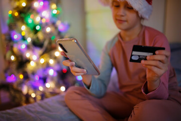 Cute preteen kid girl with phone and bank card, Christmas shopping online
