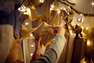 Magic photo. child with an advent calendar in eco-rust paper and garland lights.