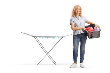 Full length portrait of a woman with a laundry basket next to a drying rack