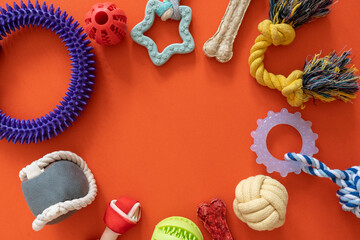Frame with dogs rubber and textile toys, snacks, bones on orange background. Close up. Accessories for dogs