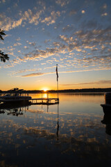 sunburst sunrise over glassy lake with clouds reflecting