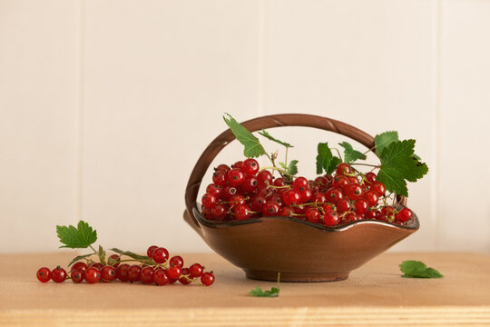 red currant berries in a vase on a wooden table