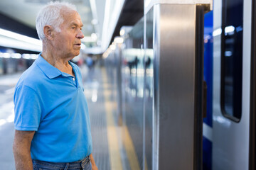 Elderly man getting on modern subway car. Concept of daily city trips