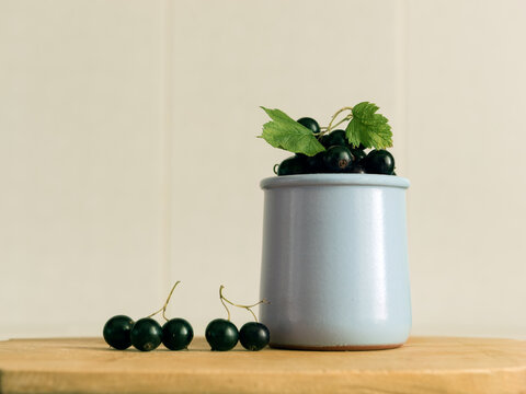 black currant berries in a vase on a wooden table