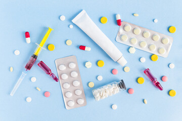 medicines, ointment, syringe, ampoules, tablets are laid out on a blue background