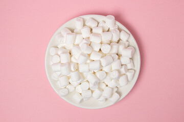 Mini marshmallows on a pink background. A plate full of marshmallows. Dessert ingredient