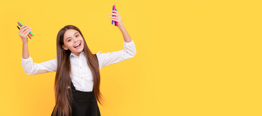 Happy school girl hold felt-tips yellow background, artistic education. Banner of schoolgirl student. School child pupil portrait with copy space. © Olena