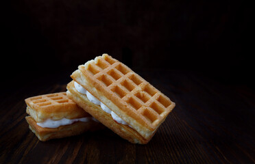 Viennese waffles with cream lie on a wooden table.