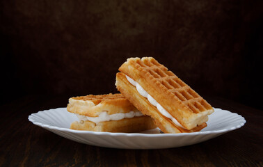 Fresh Viennese waffles with white cream on a white plate.