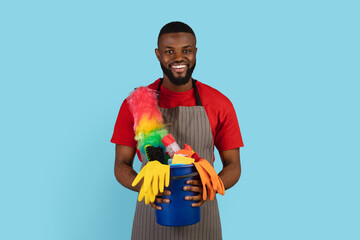Spring Cleaning. Portrait Of Smiling Black Cleaner Guy Holding Basket Of Detergents
