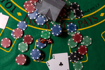 poker chips, money, toy house on blackjack table