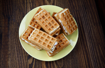 A pile of fresh Viennese waffles lie on a yellow plate.