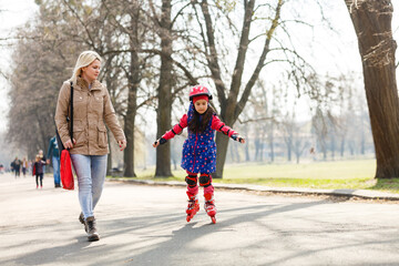 Mother and her daughter wearing roller skates in park