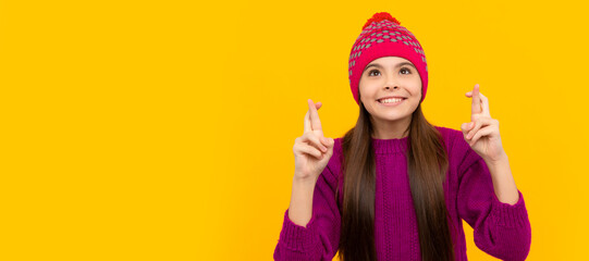 happy teen girl wear knitted hat crossed fingers making wish, winter fashion. Child face, horizontal poster, teenager girl isolated portrait, banner with copy space.