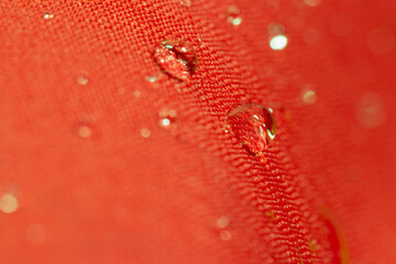 Rain droplets on a red waterproof fabric  background
