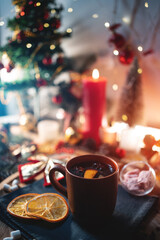 mulled red wine gluhwine in cup with orange, christmas decor table with candles