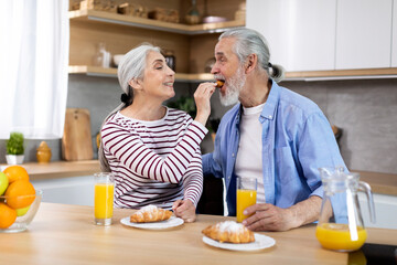 Romantic Senior Spouses Having Breakfast Together In Kitchen At Home