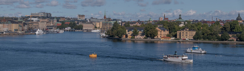Fototapeta na wymiar Panorama view over the bay Saltsjön, the old town Gamla Stan, commuting boats, a harbor ferry and a steam commuting boat leaving for the archipelago a sunny autumn day in Stockholm