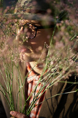 Portrait of cheerful man wearing eyeglasses and hat hiding in fresh flower bouquet. Fresh spring flowers. Mother's Day, Valentine's Day or International Women's Day concept. High quality photo