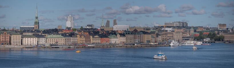 Panorama view over the bay Saltsjön, the old town Gamla Stan, commuting boats, a harbor ferry and...