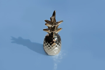 Closeup of the decoration for home like a golden pineapple isolated on a pastel blue background