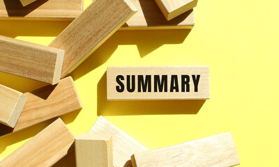 SUMMARY text written on a wooden blocks on a yellow background.