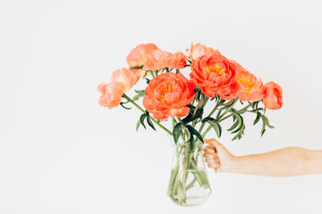 vase with peonies in woman's hand on a white background