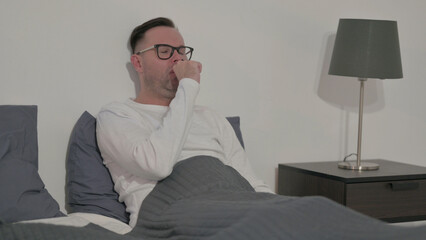 Casual Man Coughing while Sitting in Bed