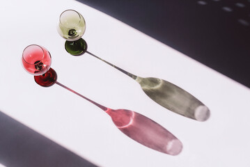 Two wine glasses on white background with light and shadow, top view
