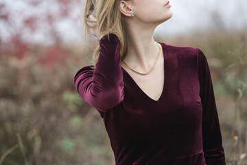 Autumn fashion outdoor portrait of young woman in purple red plush velvet midi dress. 
