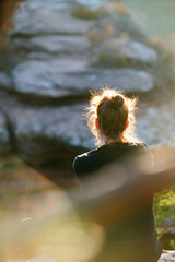 Mädchen sitzt zum Sonnenuntergang auf einem Felsen im Pfälzerwald in Rheinland Pfalz in...