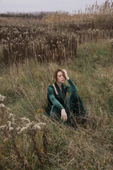 Naklejka na ściany i meble Autumn fashion outdoor portrait of young woman in emerald green set. Comfortable and trendy long sleeved shirt and trousers handmade from plush velvet
