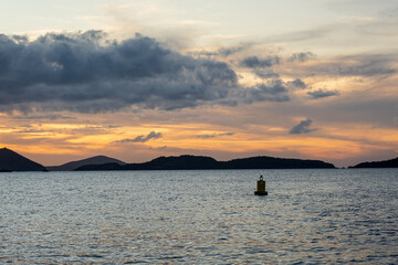 Buoy in the ocean bay at sunset with islands in the back ground - 528498285