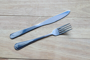 Fork and knife stainless steel isolated on wooden background closeup.