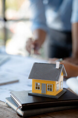 Close-up, a model of a house is placed on a table in the conference room of an architect and engineer meeting to edit a house plan designed for a housing project. Interior design and decoration ideas.