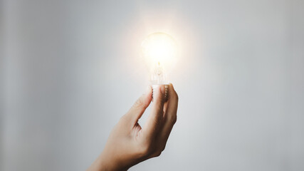 Person holding glowing lamp, Creative new idea. Innovation, brainstorming, strategizing to make the...