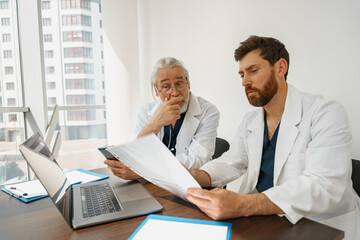 Fototapeta premium Two doctor colleagues discussing patient diagnosis sitting in office of medicine clinic