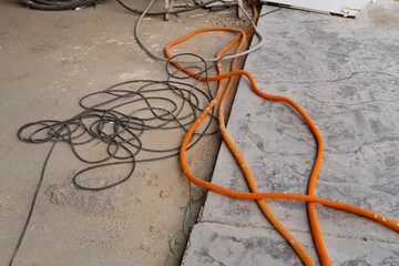 orange and black electric cables lie on the concrete floor of an unfinished building. Amplifying wires. Cables for transmitting large amounts of electricity.